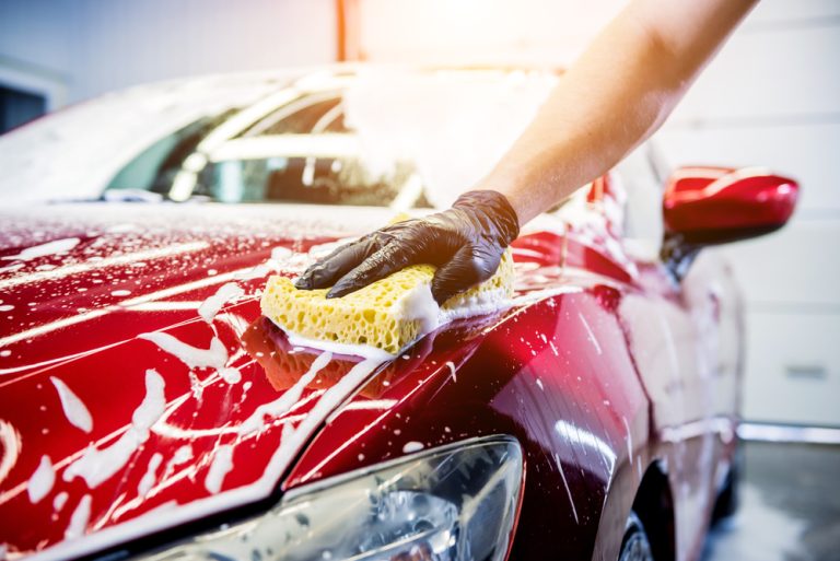 Worker hand washing red car